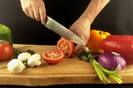 Cuchillo de acero damasco RANTY demostrando su precisión y capacidad de corte en vegetales frescos sobre tabla de madera natural.