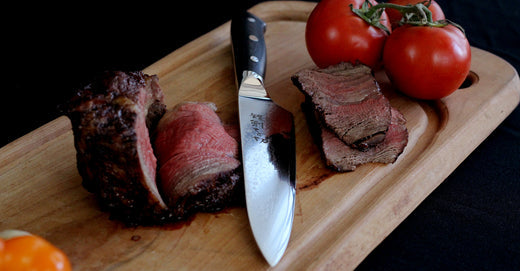 Cuchillo RANTY Grand Chef de acero de damasco mostrando su precisión y calidad en cortes perfectos de carne sobre tabla de madera.