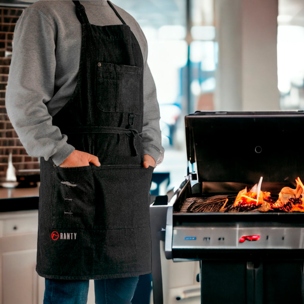 Delantal de cocina vintage jeans Ranty negro en uso junto a parrilla encendida.