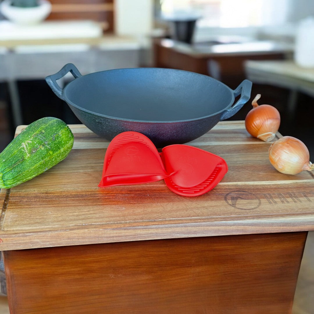 Mangos de silicona Ranty rojos en uso para wok de hierro fundido sobre tabla de corte, junto a verduras frescas.