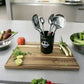 Set seis utensilios cocina Joven Ranty en balde sobre tabla madera con verduras frescas, diseño moderno y de acero inoxidable.
