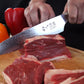 Cuchillo de acero de Damasco Grand Chef Ranty 20cm cortando carne con precisión.